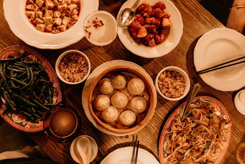 Chinese dishes and dumplings shared across a wooden table