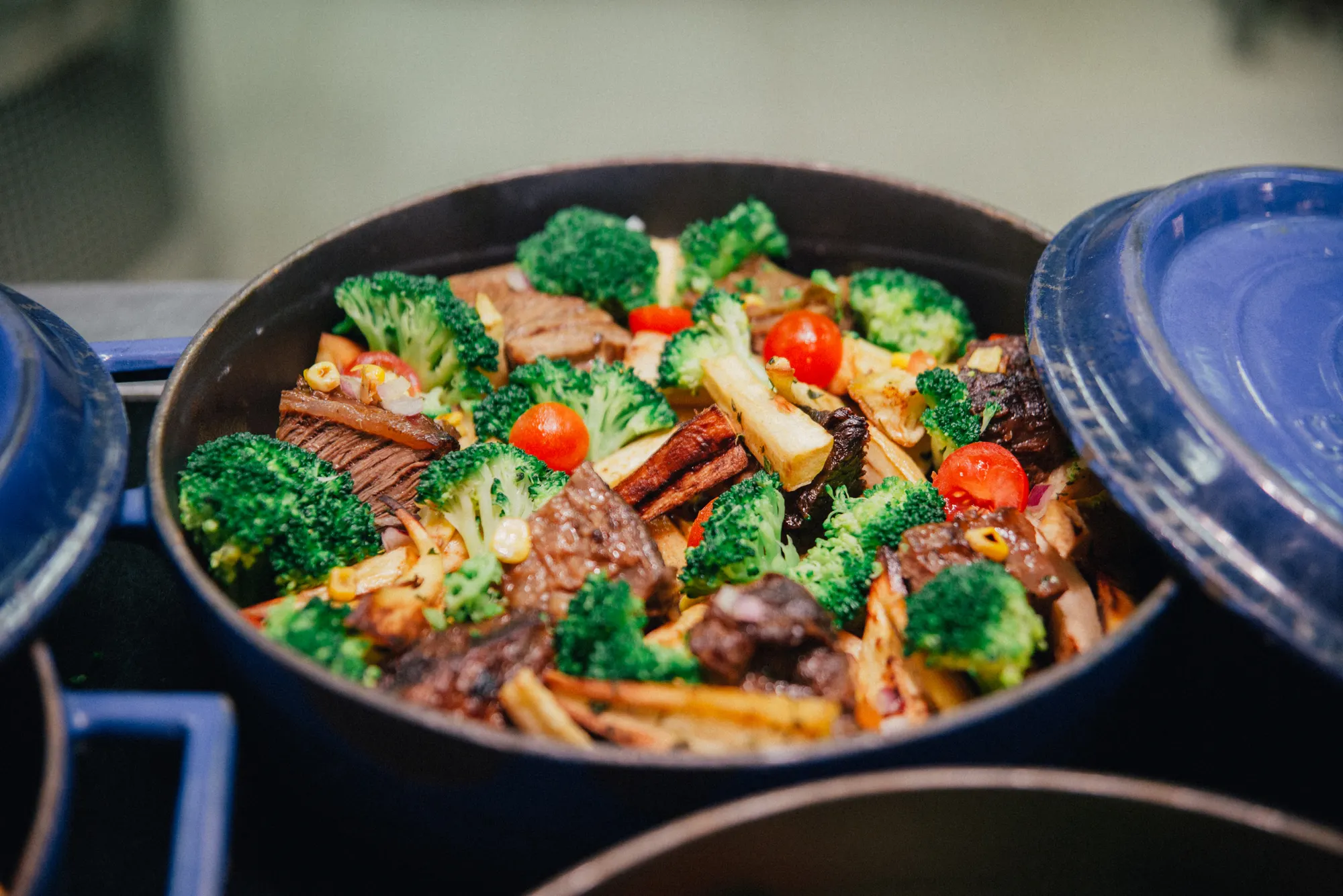 Beef and broccoli stir fry with peppers in a dark pan