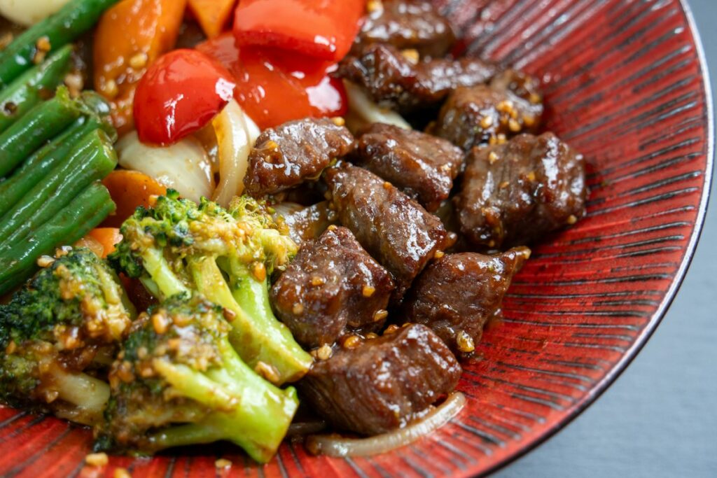 Beef and broccoli stir fry on a red plate