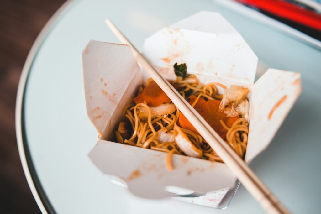Noodles in a takeout box with chopsticks